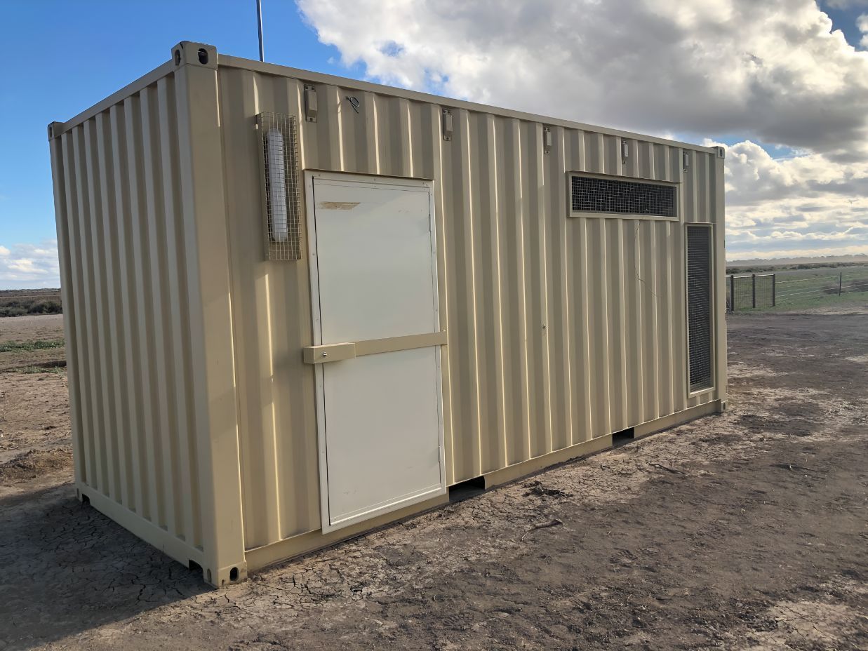 A Shipping Container With a White Door is Sitting in the Middle of a Dirt Field — OSM Transportables In Parkes, NSW