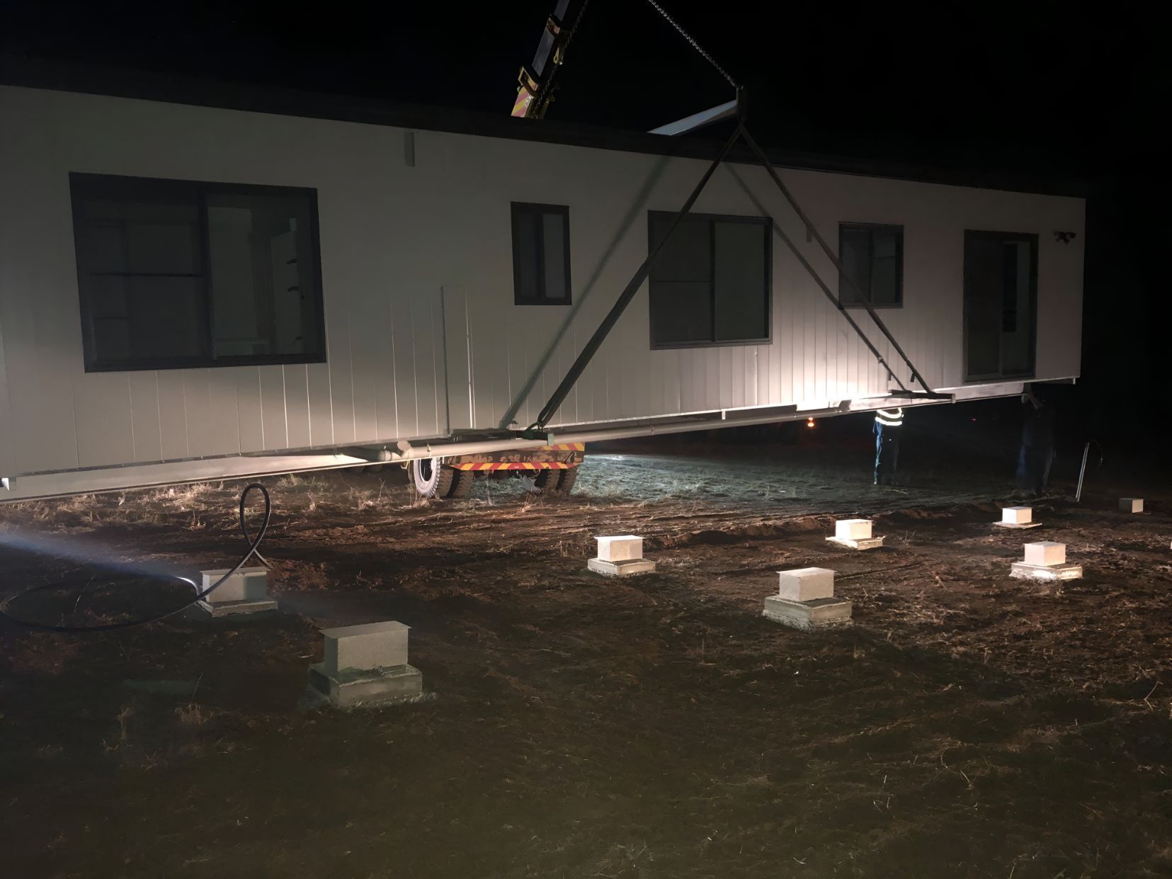 A Mobile Home is Being Lifted by a Crane at Night — OSM Transportables In Forbes, NSW