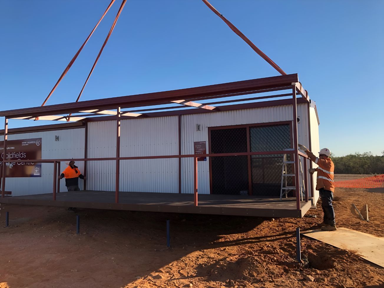 A Crane is Lifting a White Building With a Red Roof — OSM Transportables In Forbes, NSW