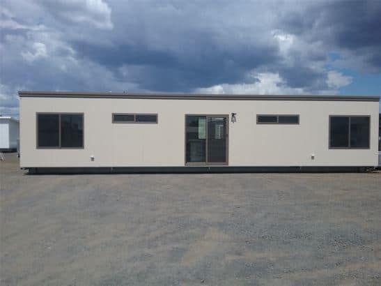 Front View of a Long, White Portable House Featuring Glass Windows and a Sliding Door — OSM Transportables In Dubbo, NSW