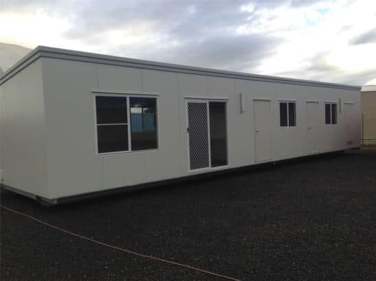 Side View of a White, Elongated Portable House With Glass Windows and a Sliding Door — OSM Transportables In Dubbo, NSW