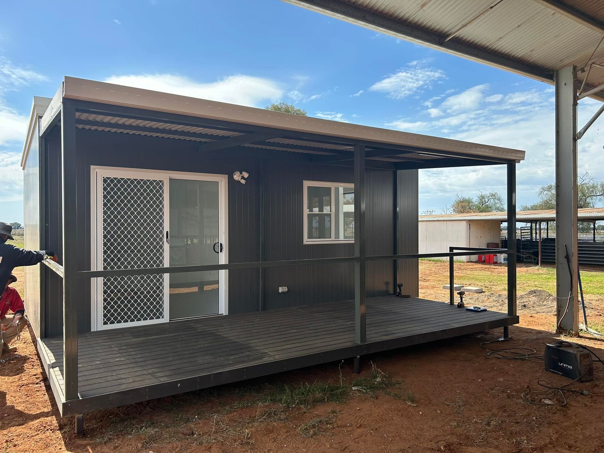 A Dark-colored, Modern Portable Cabin Featuring a Front Porch With a Sliding Glass Door — OSM Transportables In Dubbo, NSW