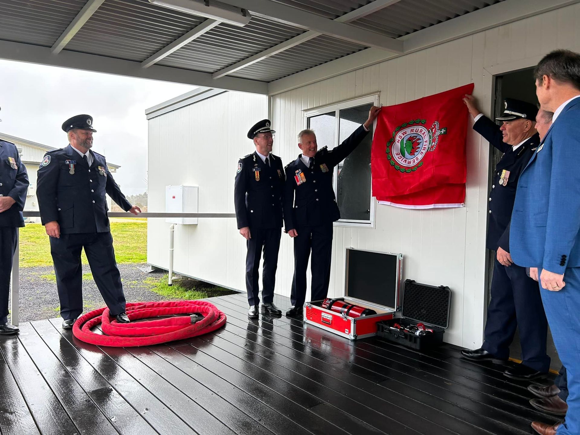 Fire Officials in Uniform Unveil a Red Flag on a Building Deck — OSM Transportables In Dubbo, NSW