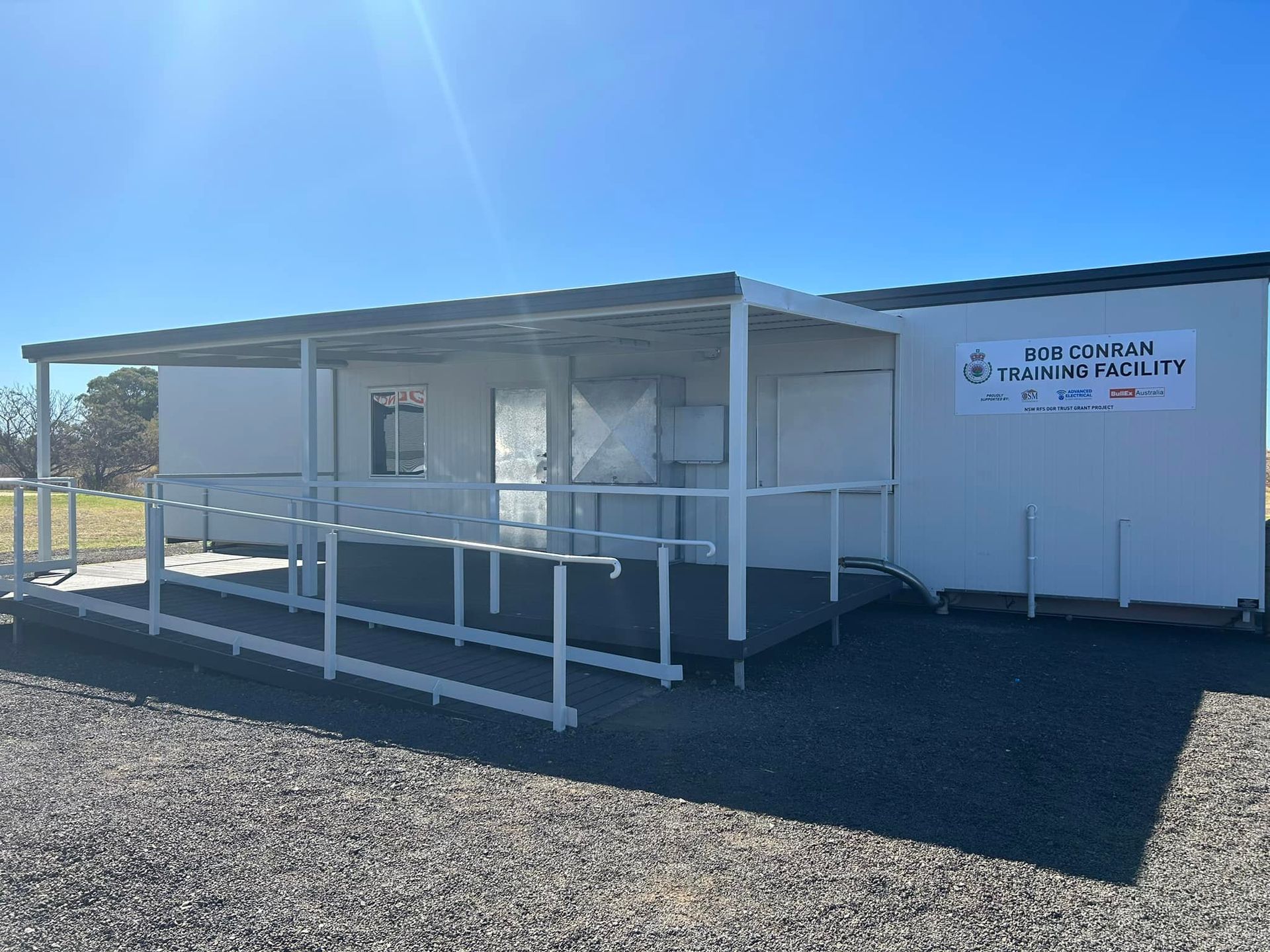 A modular building named the Bob Graham Training Facility, featuring a white exterior, a covered porch, and a ramp.
