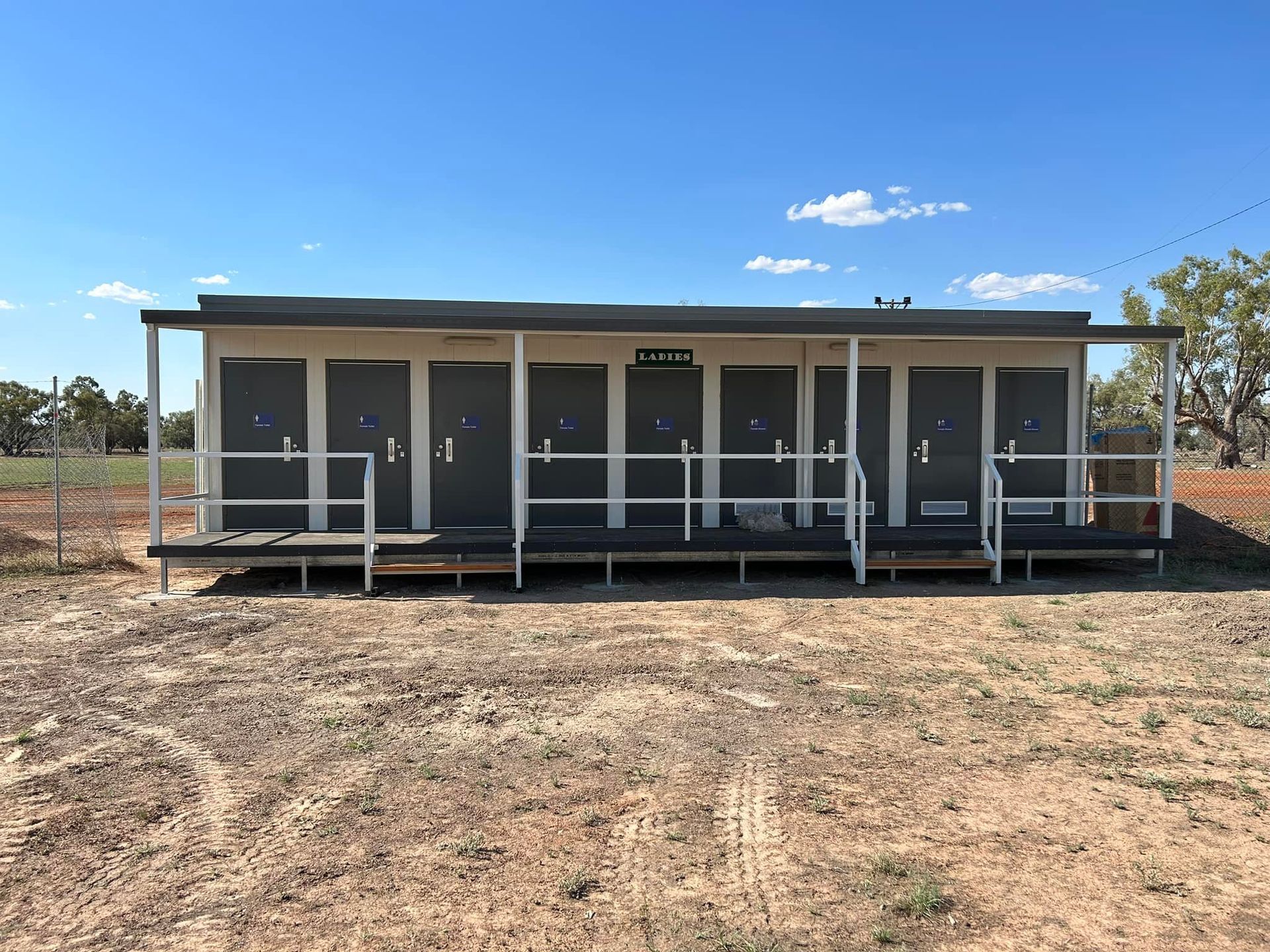 A Modular Building in a Dirt Lot Featuring Eight Individual Grey Doors — OSM Transportables In Dubbo, NSW