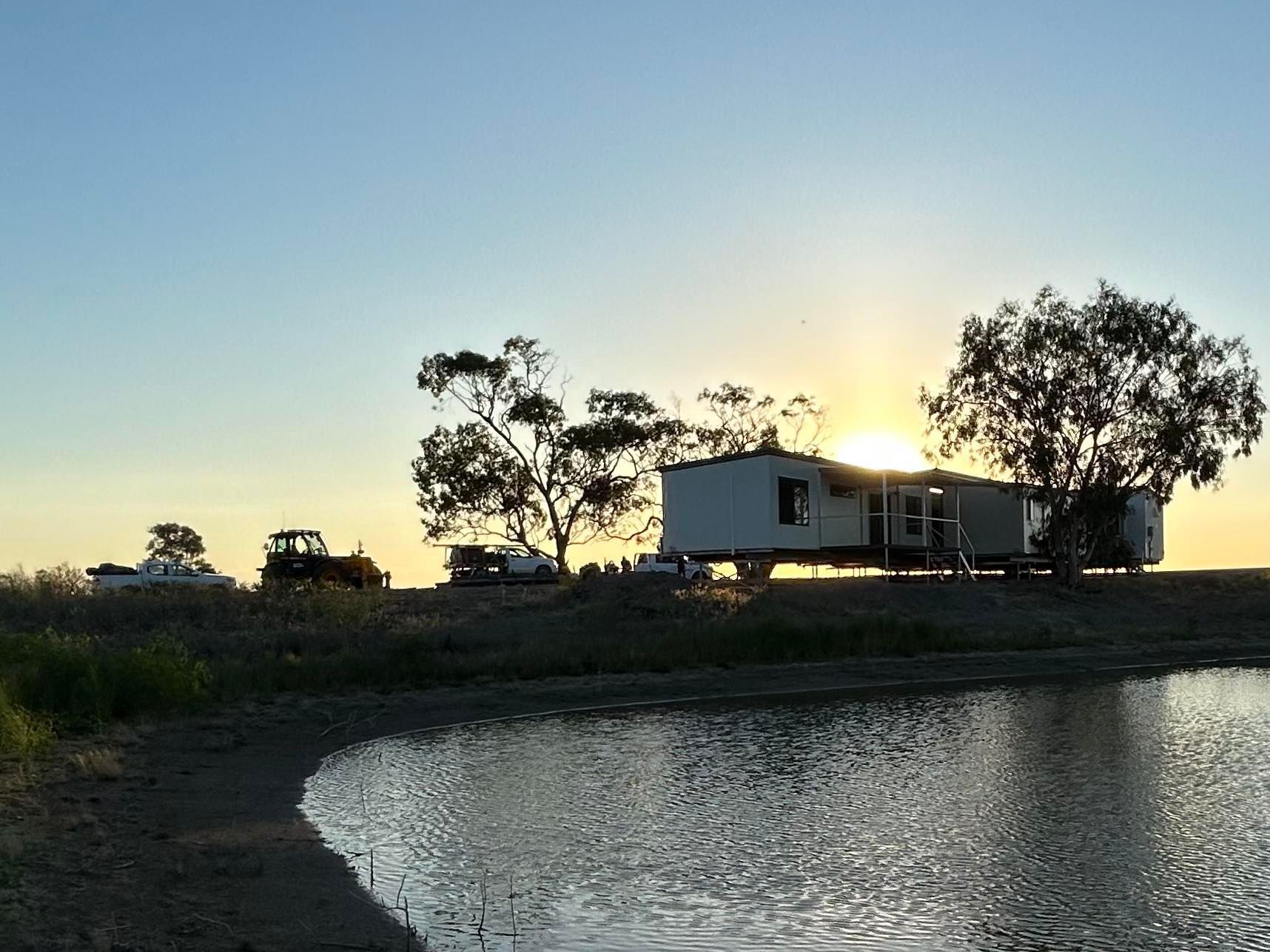 A Mobile Home Sits by a Pond at Sunset — OSM Transportables In Dubbo, NSW
