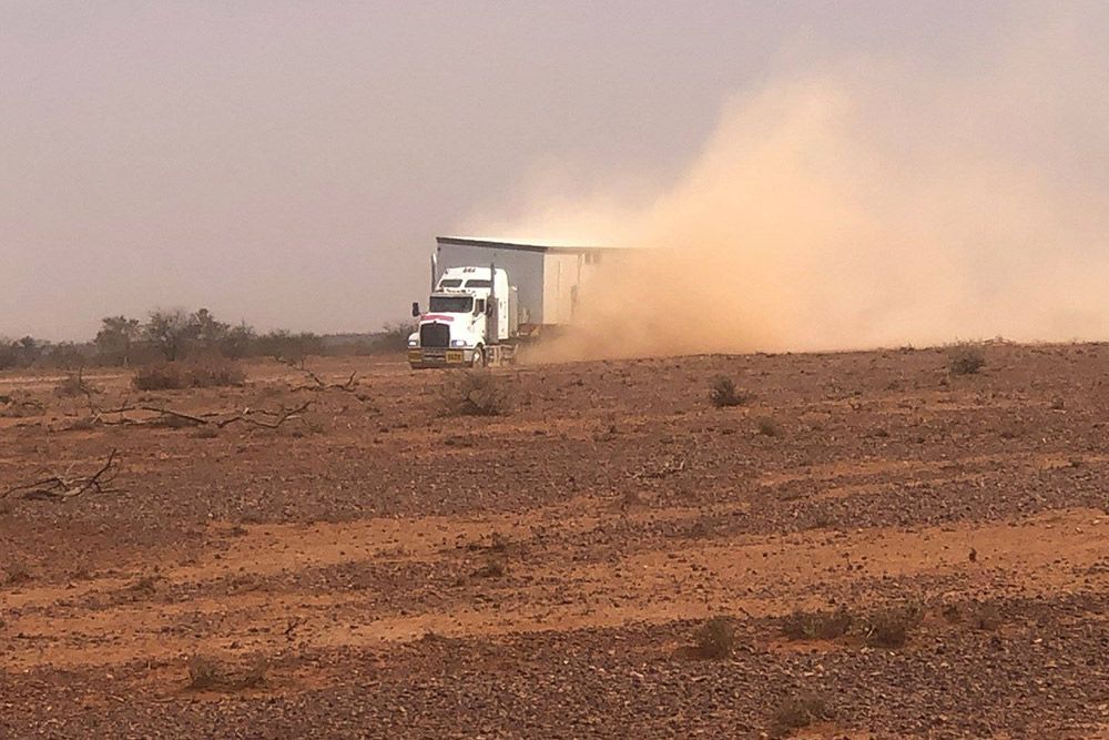 Truck Transporting a House With Sand, Emitting a Plume of Dust — OSM Transportables In Dubbo, NSW