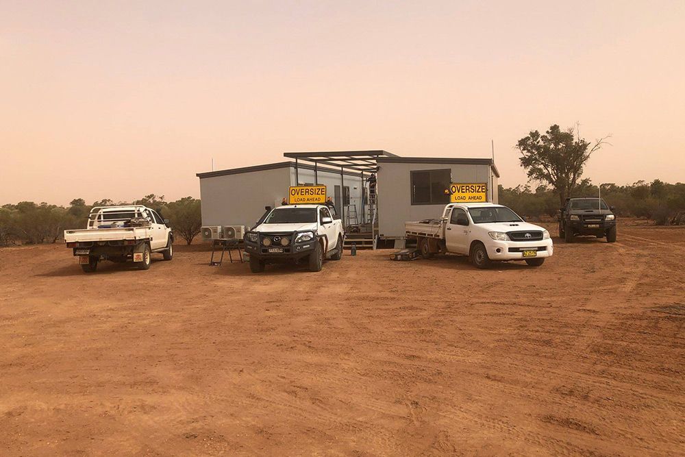 Portable House Surrounded by Four Pickup Trucks, Showcasing Versatility and Mobility — OSM Transportables In Dubbo, NSW