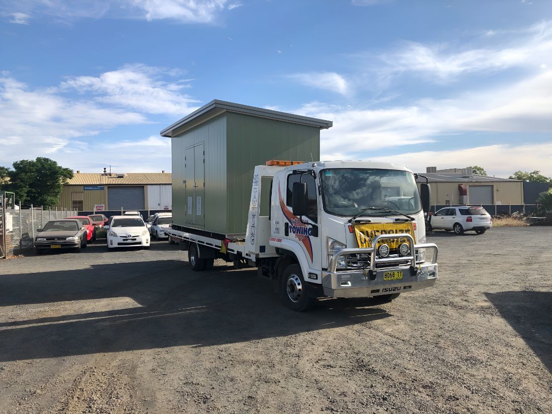 A Tow Truck is Carrying a Shed in a Parking Lot — OSM Transportables In Gunnedah, NSW