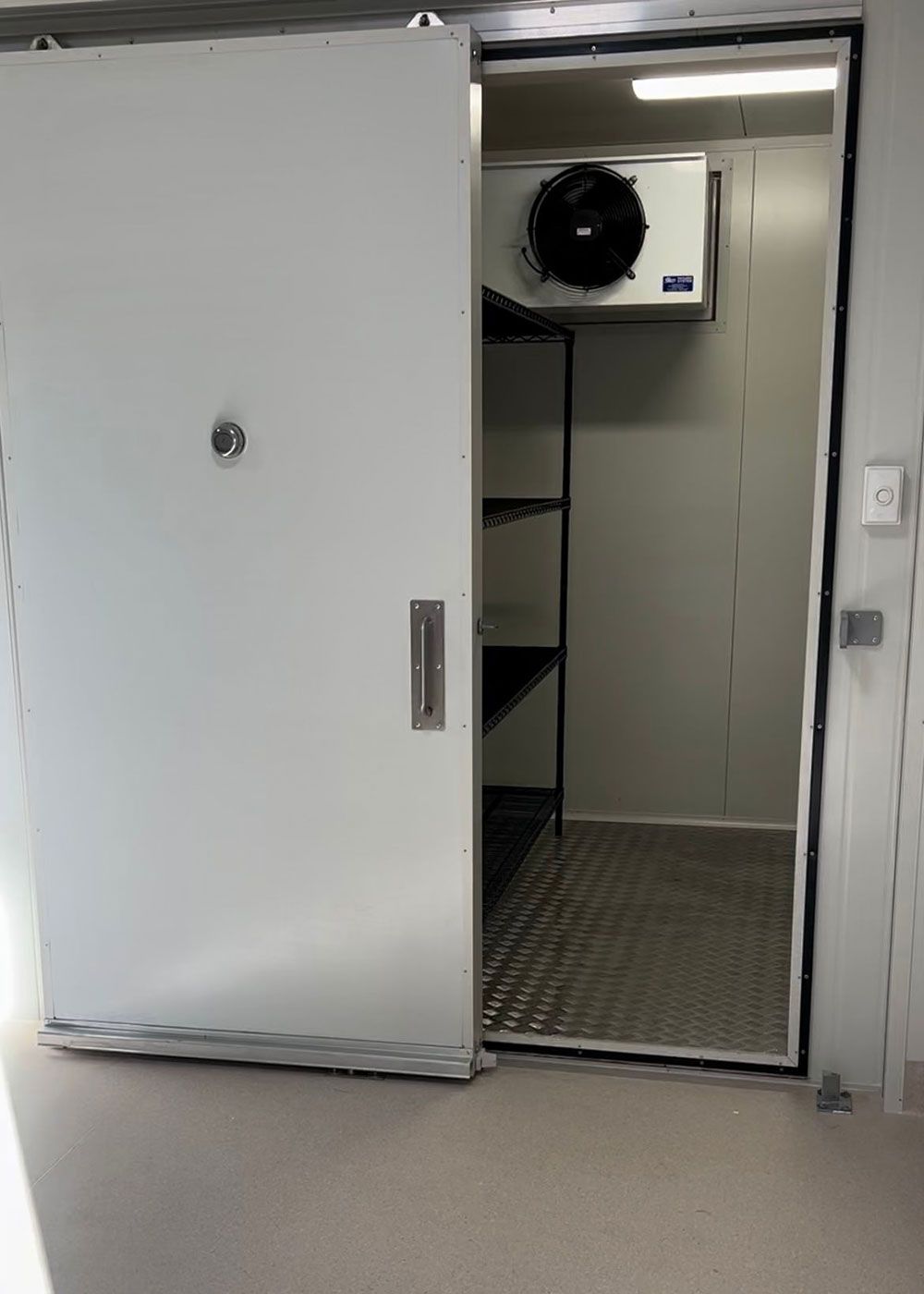 A White Sliding Door Opens to a Walk-in Commercial Refrigerator or Freezer — OSM Transportables In Dubbo, NSW