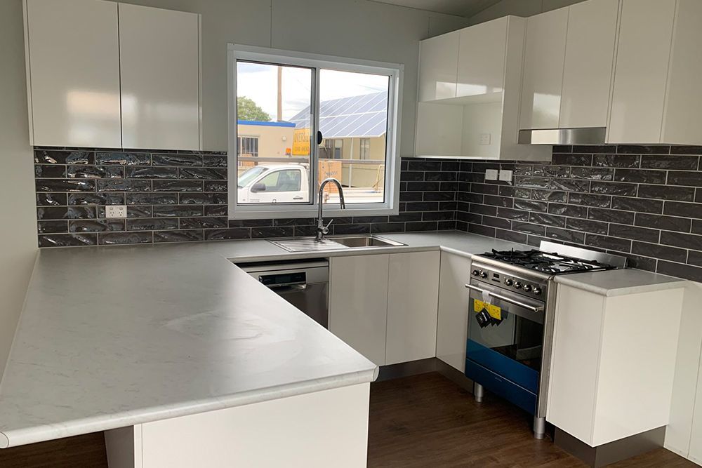 Transportable House Featuring a White Kitchen With Stylish Dark-tiled Walls — OSM Transportables In Dubbo, NSW