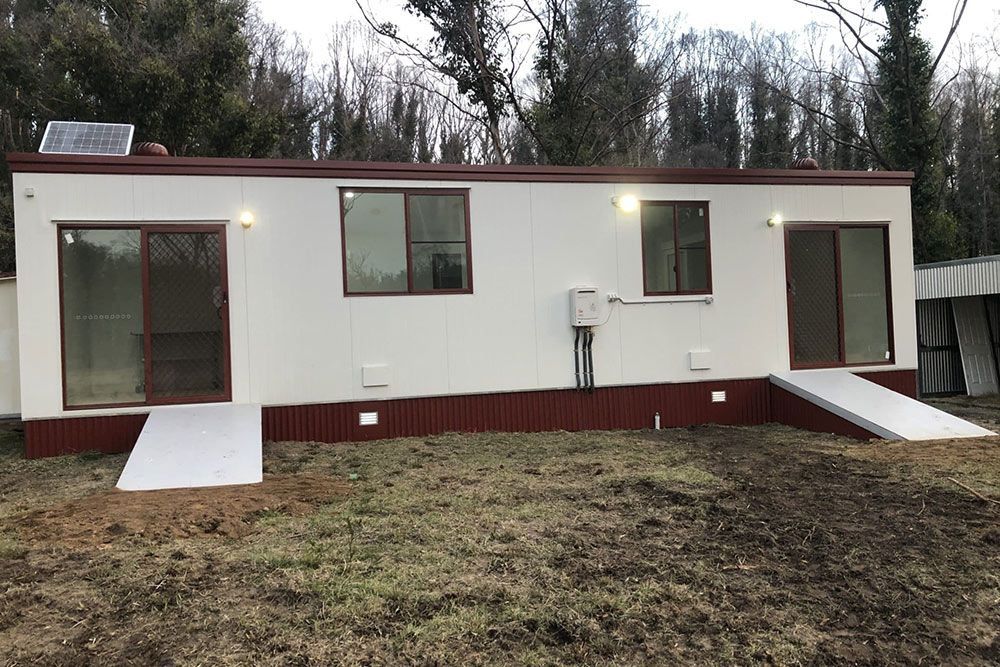 White Long Portable House With Accent of Red and Solar Panel Installed — OSM Transportables In Dubbo, NSW