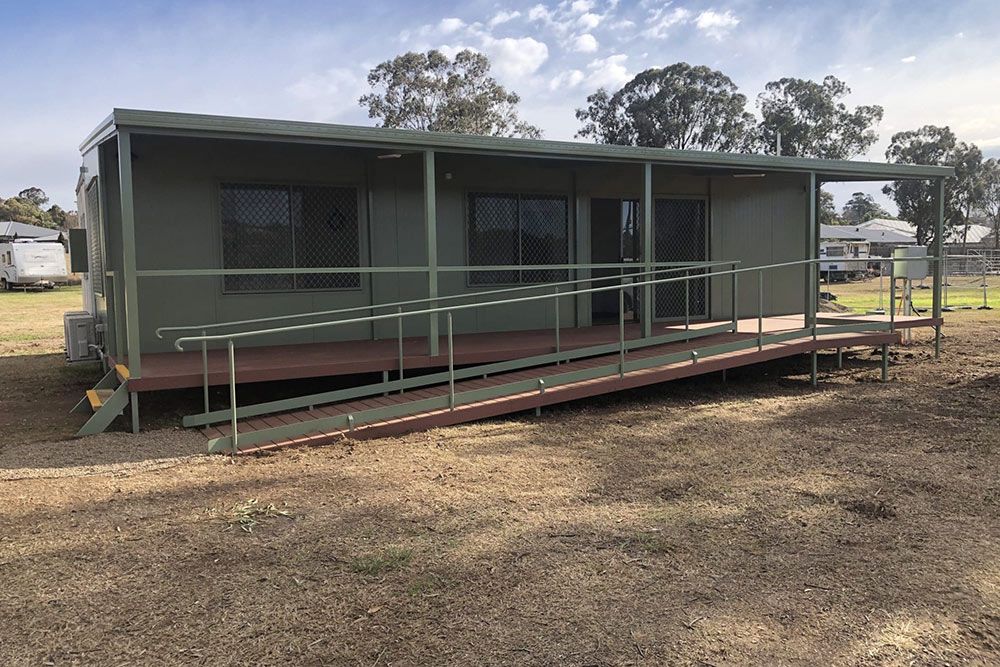 Dark Green Portable House Featuring a Lengthy Red Staircase — OSM Transportables In Dubbo, NSW