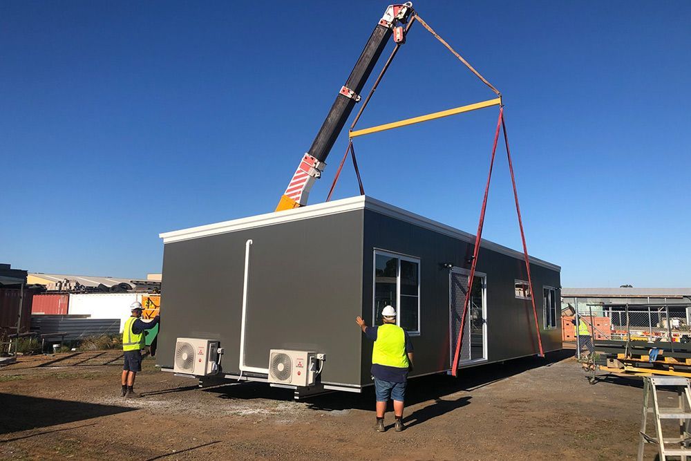 3 People Placing the Portable House on the Ground Using Crane Machine — OSM Transportables In Dubbo, NSW