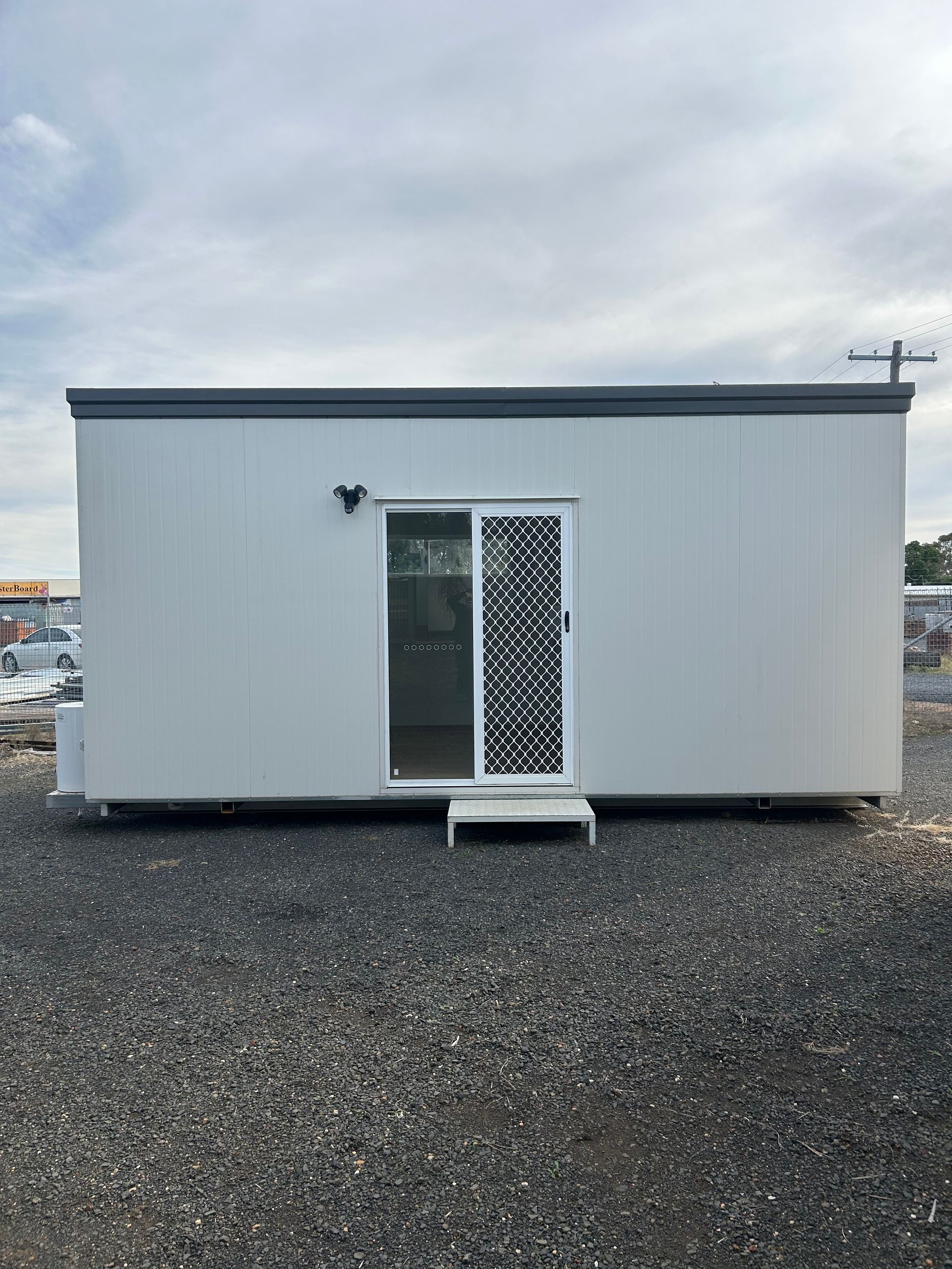 A Rectangular, Light Gray Portable Building With a White Sliding Glass Door and Screen — OSM Transportables In Dubbo, NSW