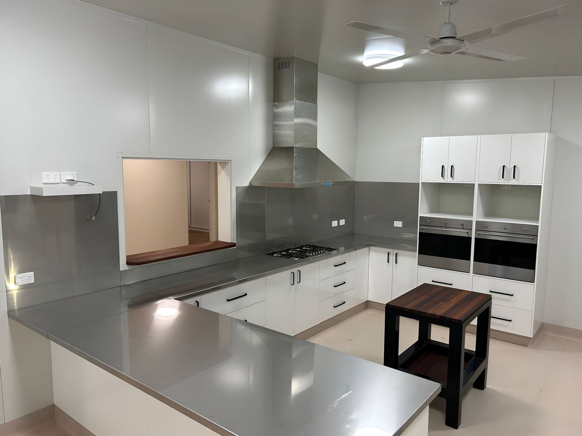 A Kitchen With Stainless Steel Counter Tops, White Cabinets, and a Wooden Table — OSM Transportables In Dubbo, NSW