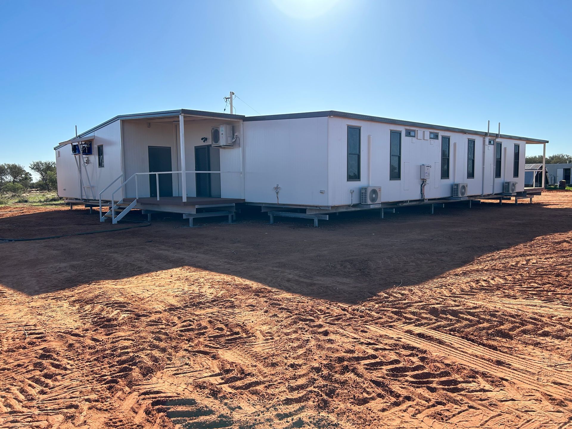 A Large White House is Sitting in the Middle of a Dirt Field — OSM Transportables In Dubbo, NSW