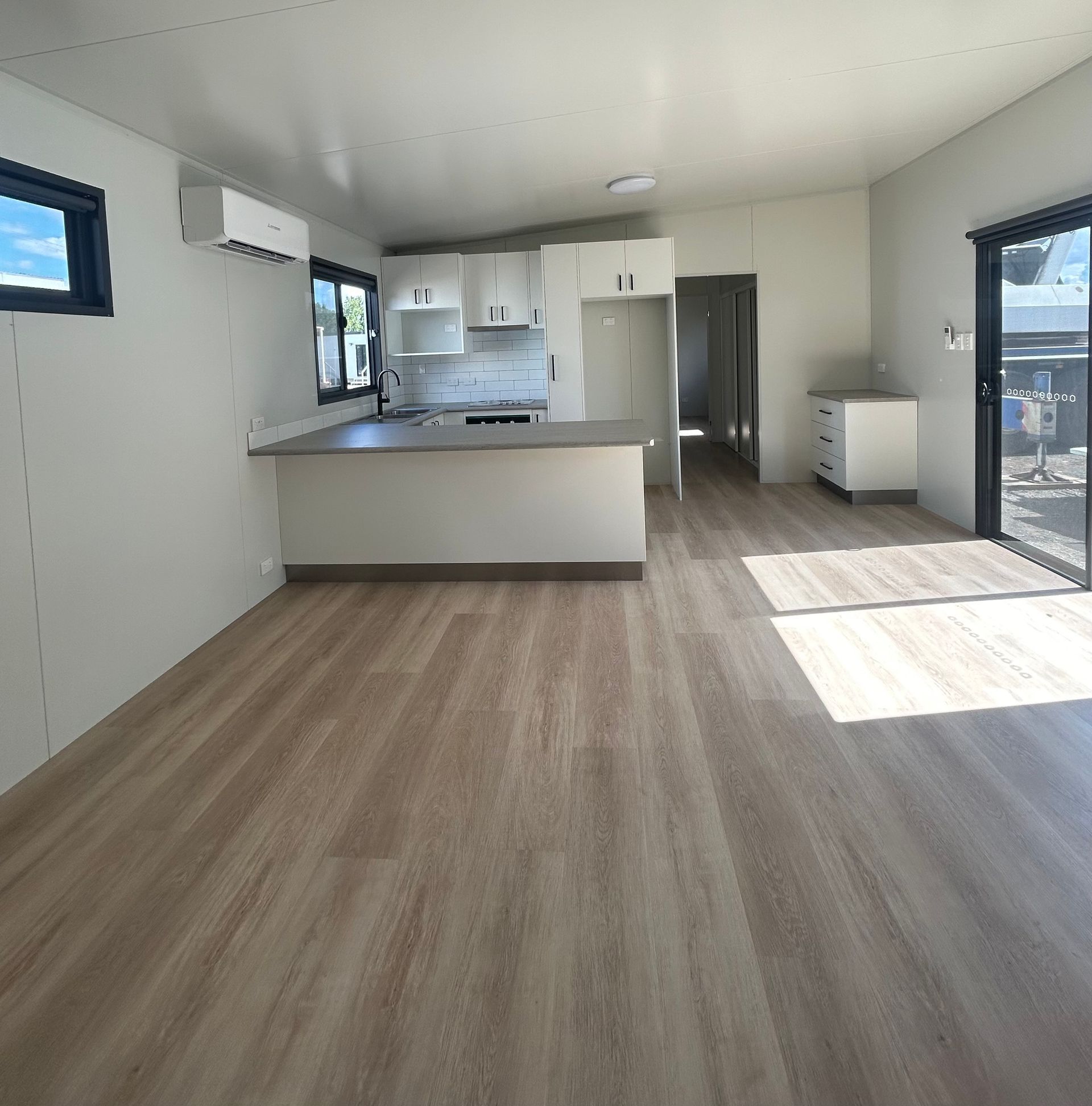 A Modern, Minimalist Kitchen and Living Space With Light Wood Floors — OSM Transportables In Dubbo, NSW