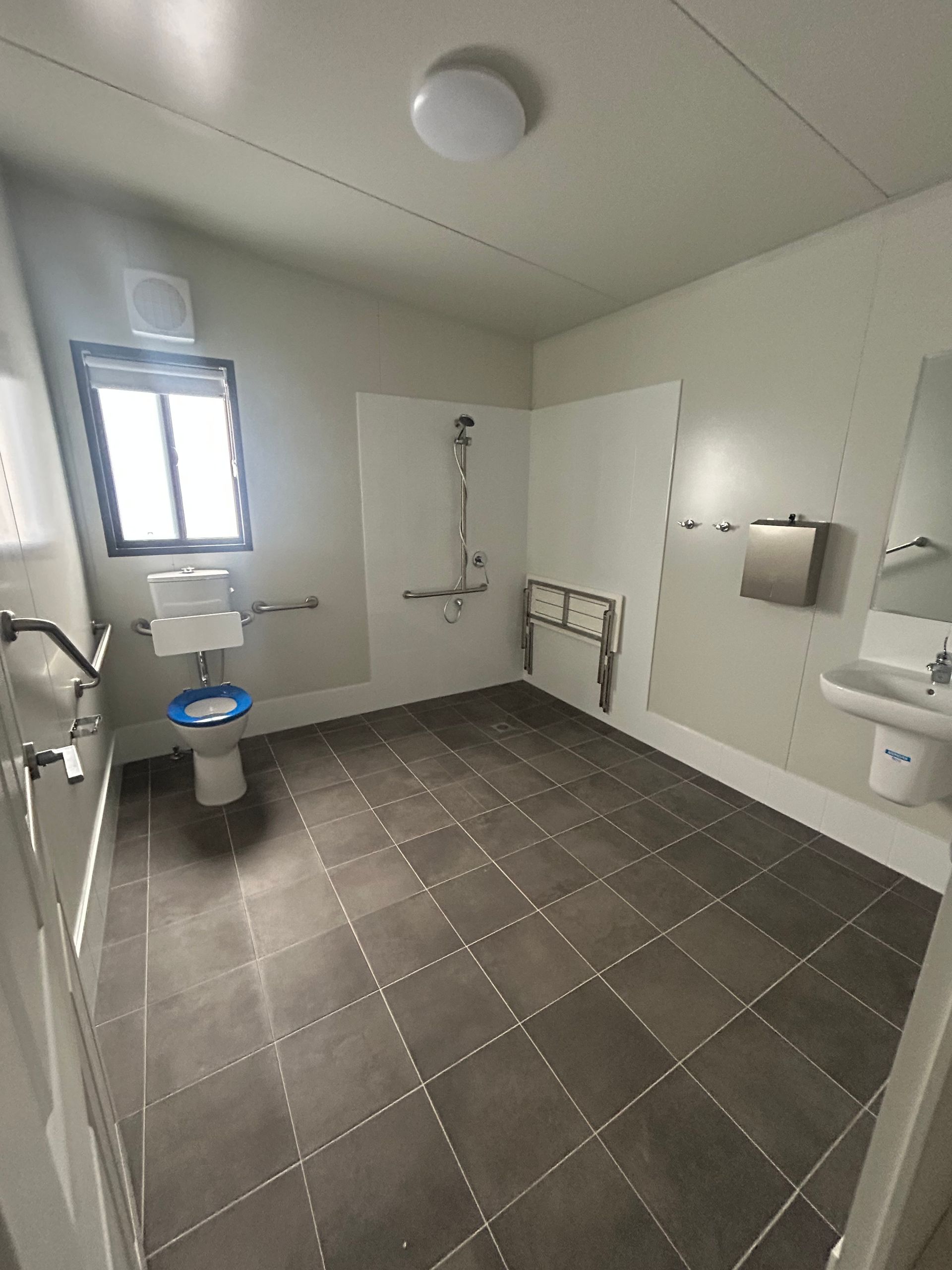 An Accessible, Spacious, Modern Restroom With Gray Tiled Floors — OSM Transportables In Dubbo, NSW