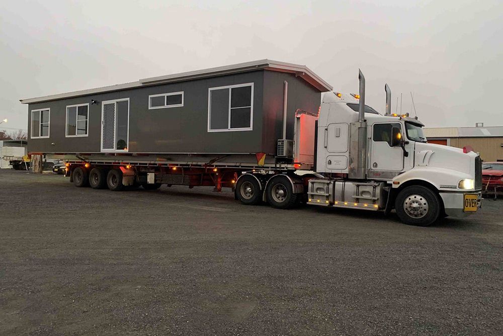 Side View Image Shot of a Portable House Loaded on the Truck Rear Tail — OSM Transportables In Dubbo, NSW
