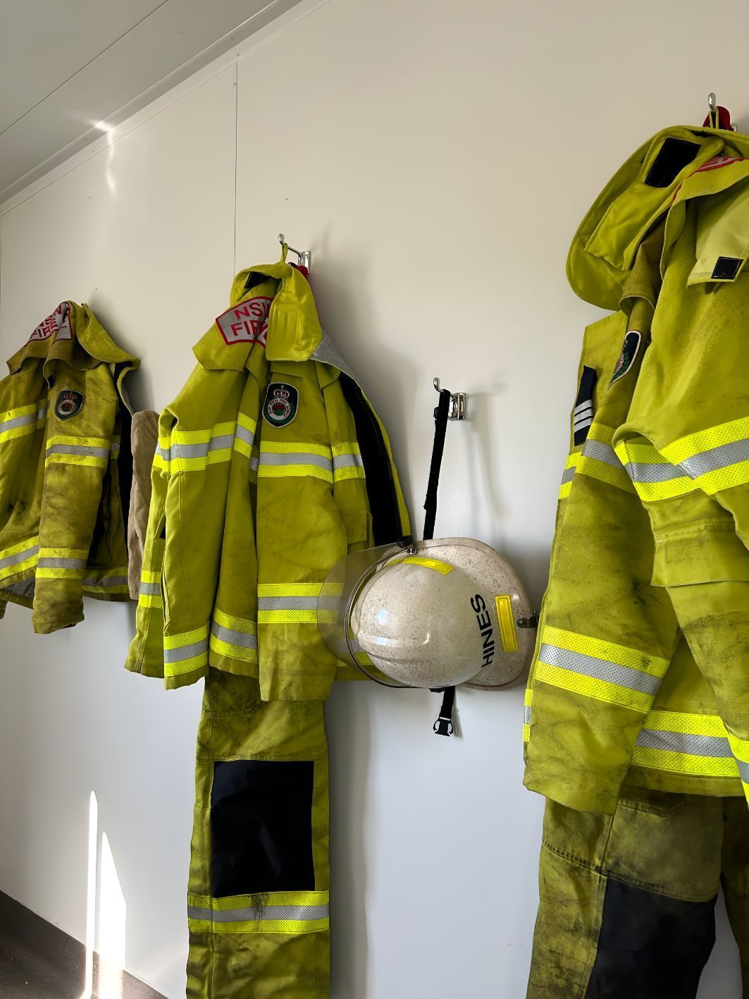 A Row of Yellow Firefighter 's Uniforms and Helmets Hanging on a Wall — OSM Transportables In Dubbo, NSW