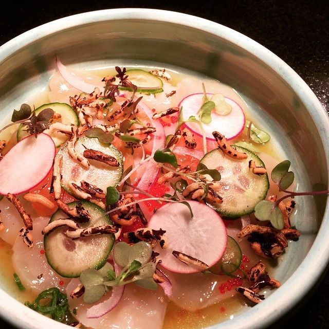 Dish of thinly sliced fish, vegetables, and garnish in a light blue bowl.