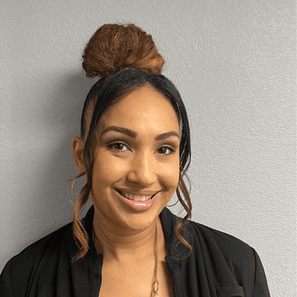 A woman with her hair in a bun is smiling for the camera.