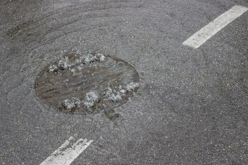 Asphalt Road With a Manhole Cover and White Painted Lines — VR Marsden Plumbing in Red Rock, NSW