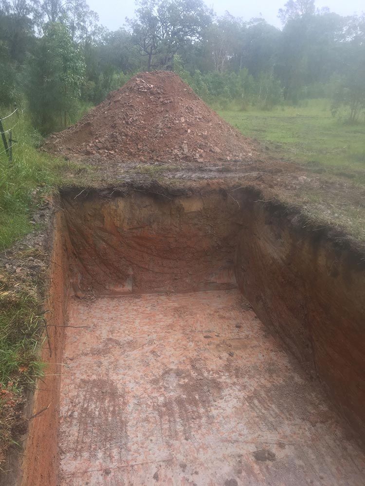 Open Rectangular Trench With Dirt Pile Next to It, in a Grassy Area — VR Marsden Plumbing in Woolgoolga, NSW