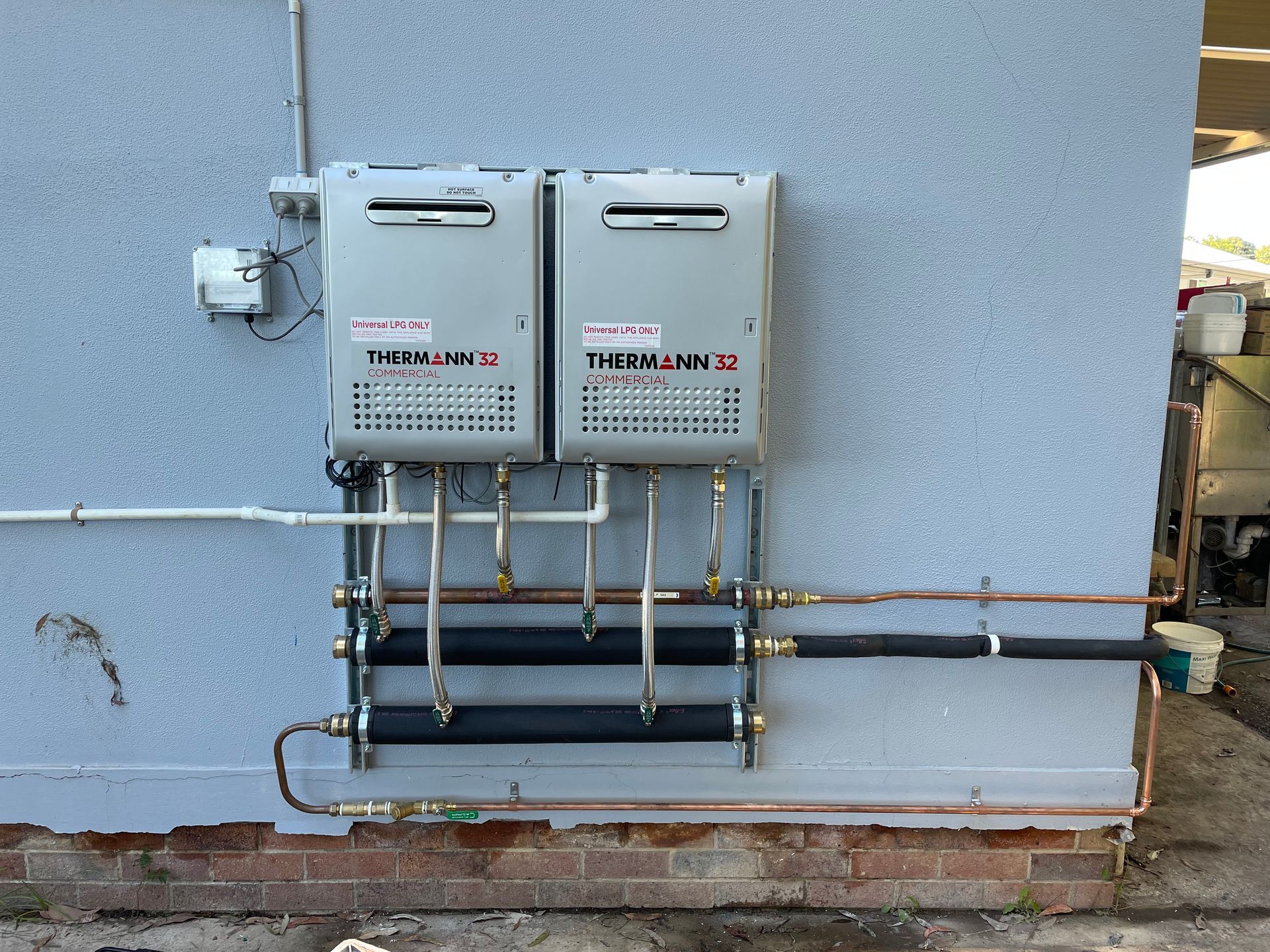 Two plumbing like systems are on the outside of a building wall with plumbing joint to it — VR Marsden Plumbing in Red Rock, NSW