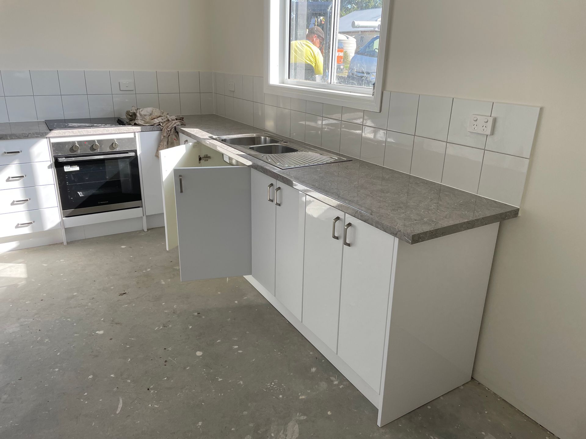 Newly installed kitchen cabinets with gray countertops and sink, near a window and stove— VR Marsden Plumbing in Red Rock, NSW