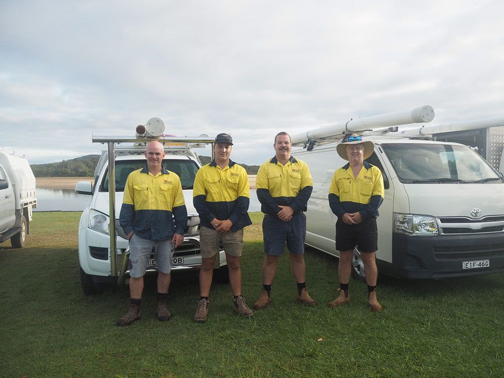 Four Workers in Uniform Stand in Front of Vehicles — VR Marsden Plumbing in Red Rock, NSW