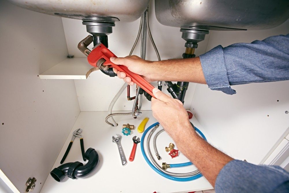 A Plumber Working Under a Kitchen Sink — VR Marsden Plumbing in Red Rock, NSW