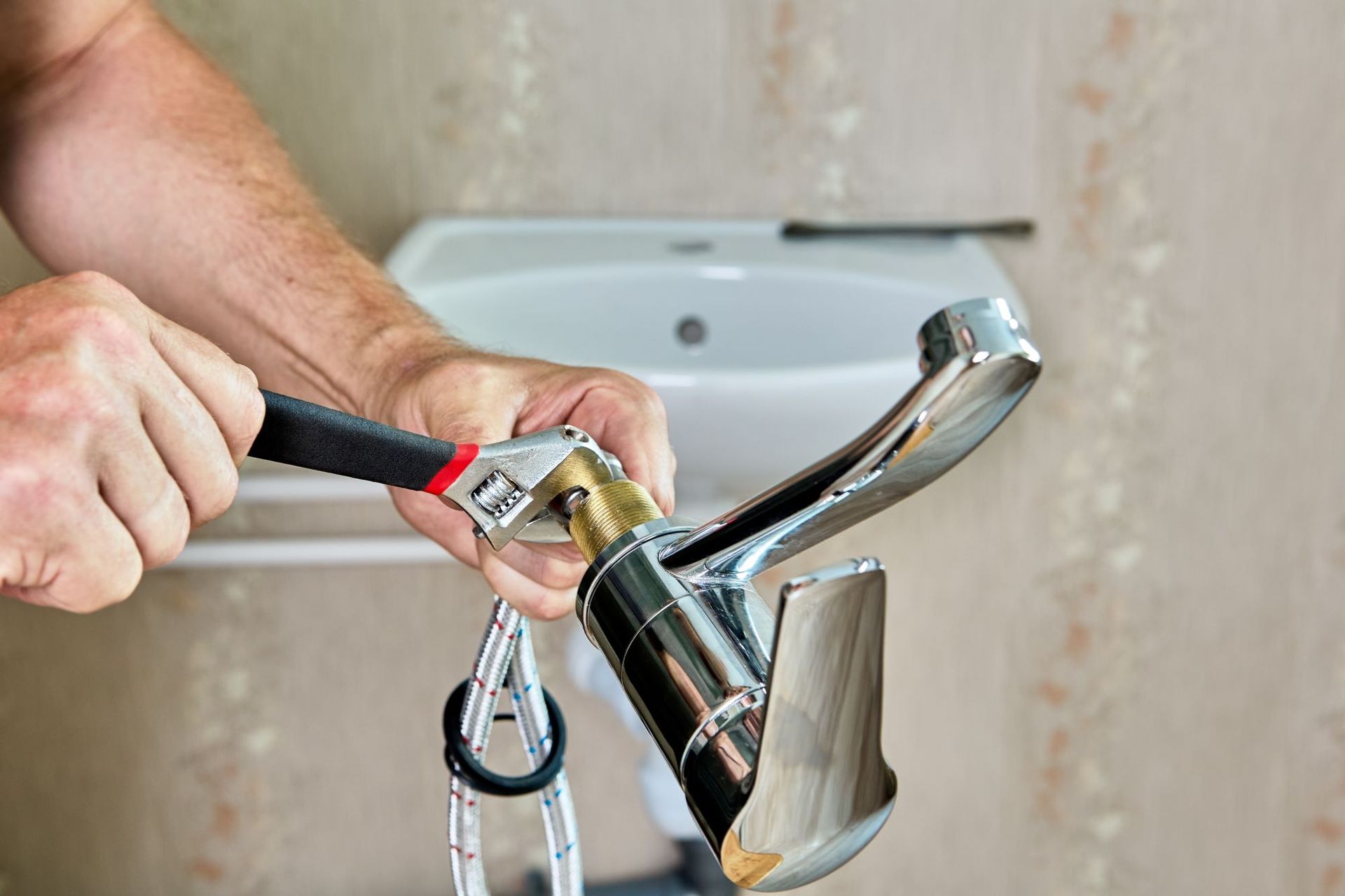 Person Using Wrench to Repair Chrome Faucet in Bathroom Sink — VR Marsden Plumbing in Red Rock, NSW