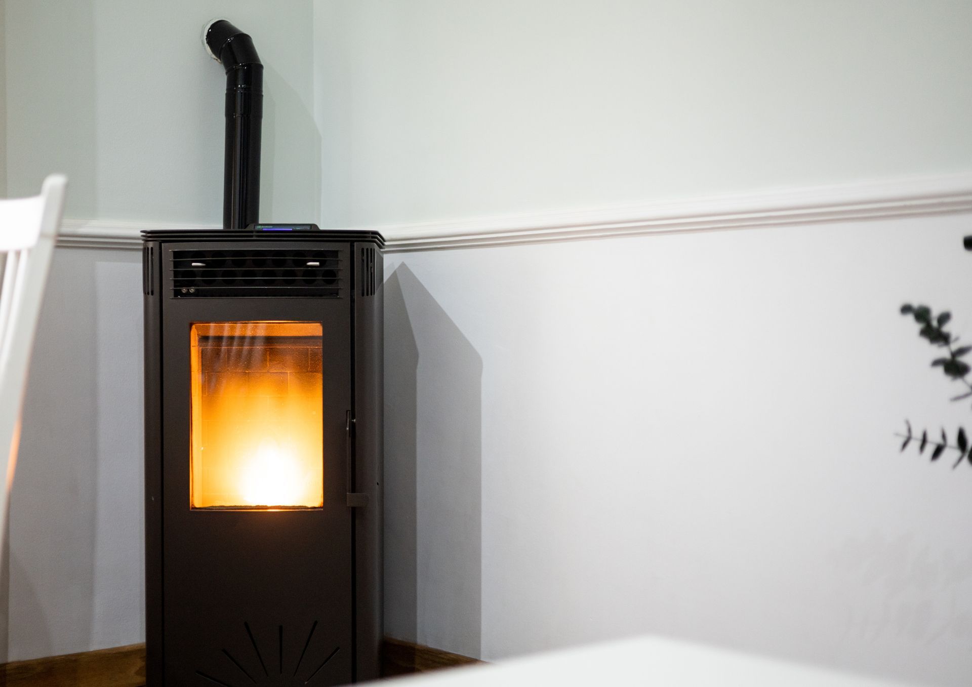 Black wood stove with a bright fire burning in a white-walled room