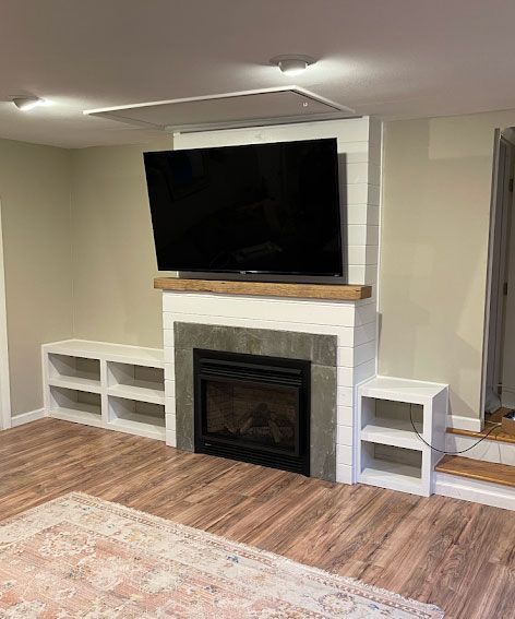 Living room with fireplace, wall-mounted TV, white shelving, and wood flooring