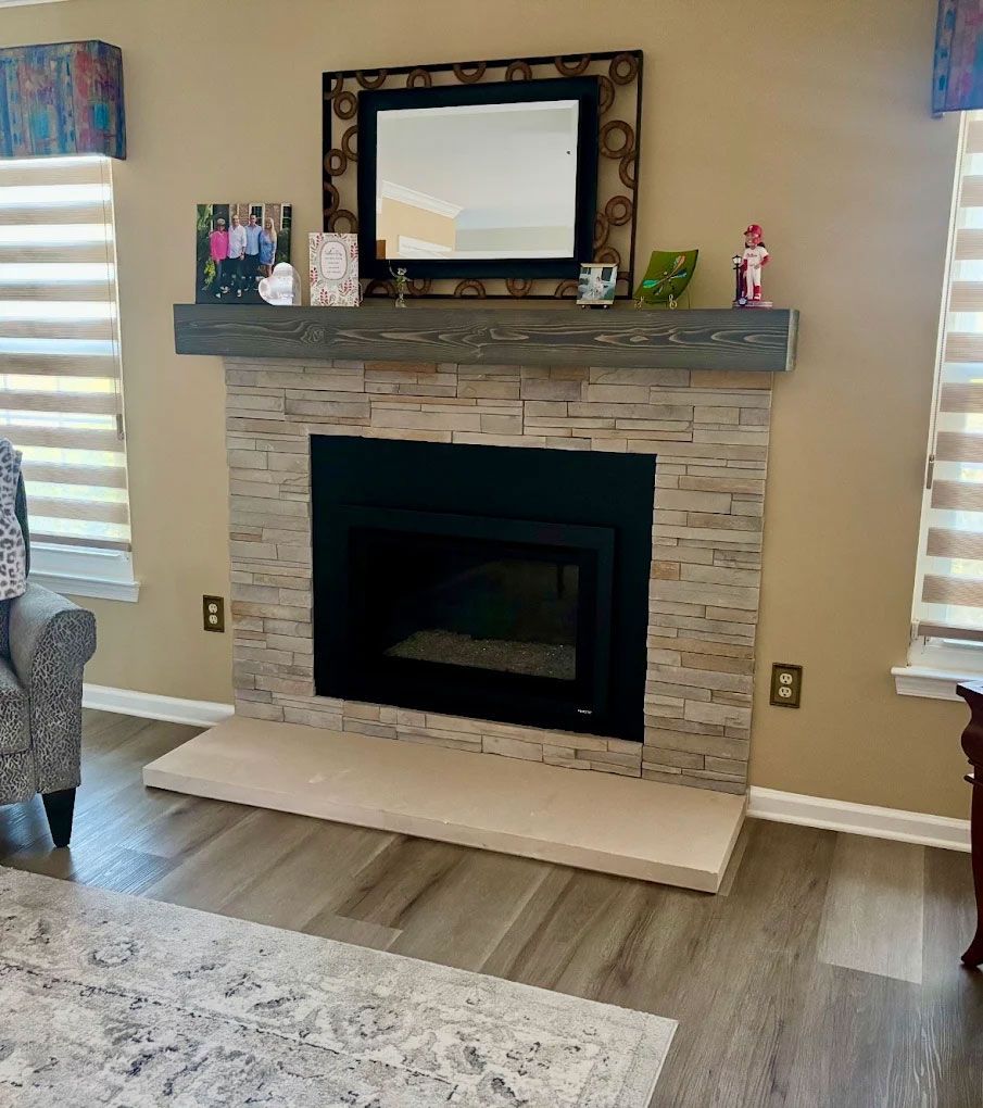 Living room fireplace with stone surround, gray mantel, mirror, and striped window shades