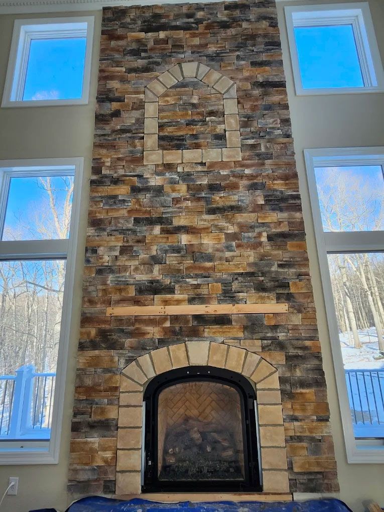 Stone fireplace wall with arched firebox, decorative niche, and tall windows on both sides