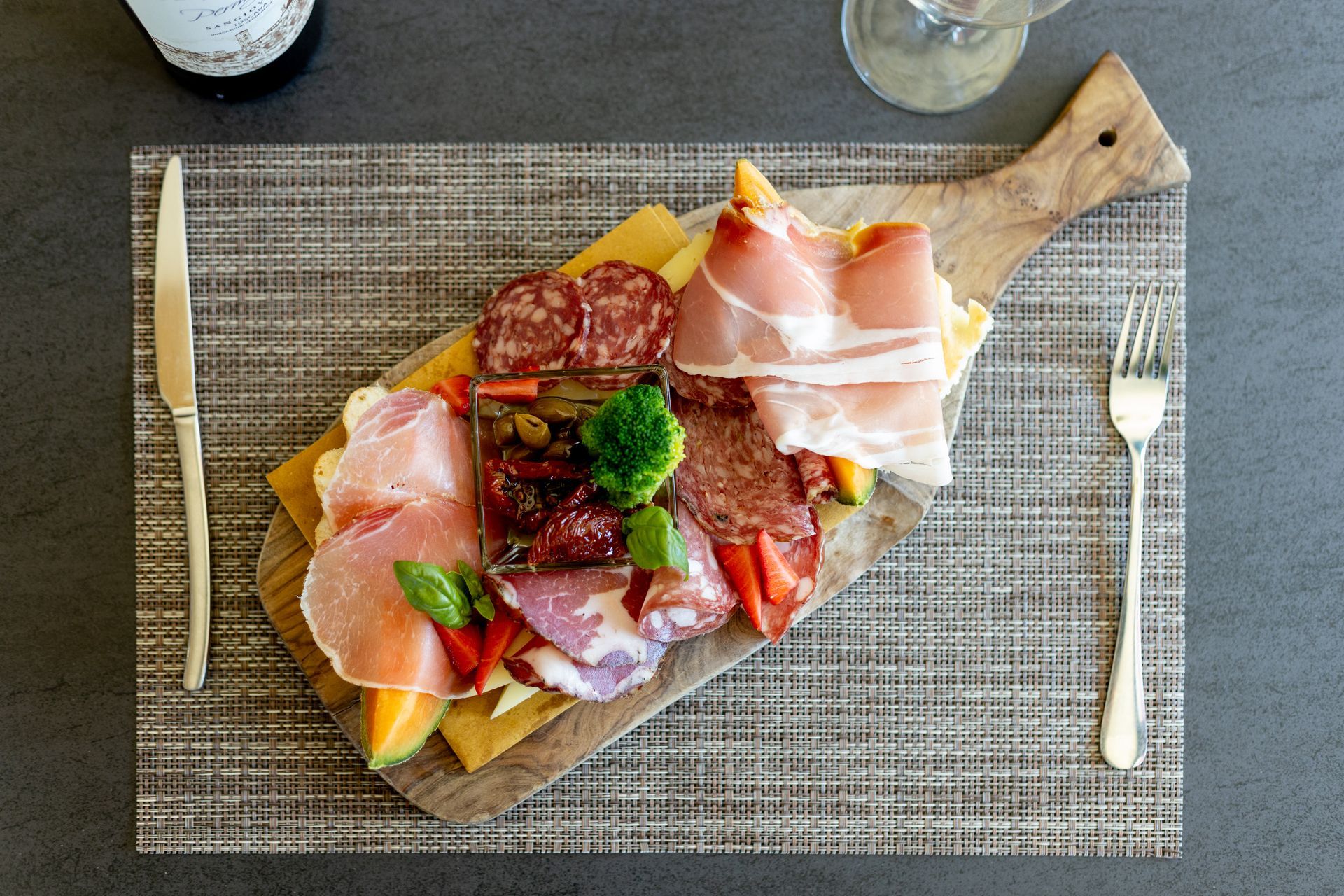 Tagliere di salumi, formaggi, frutta e pane su un vassoio di legno.