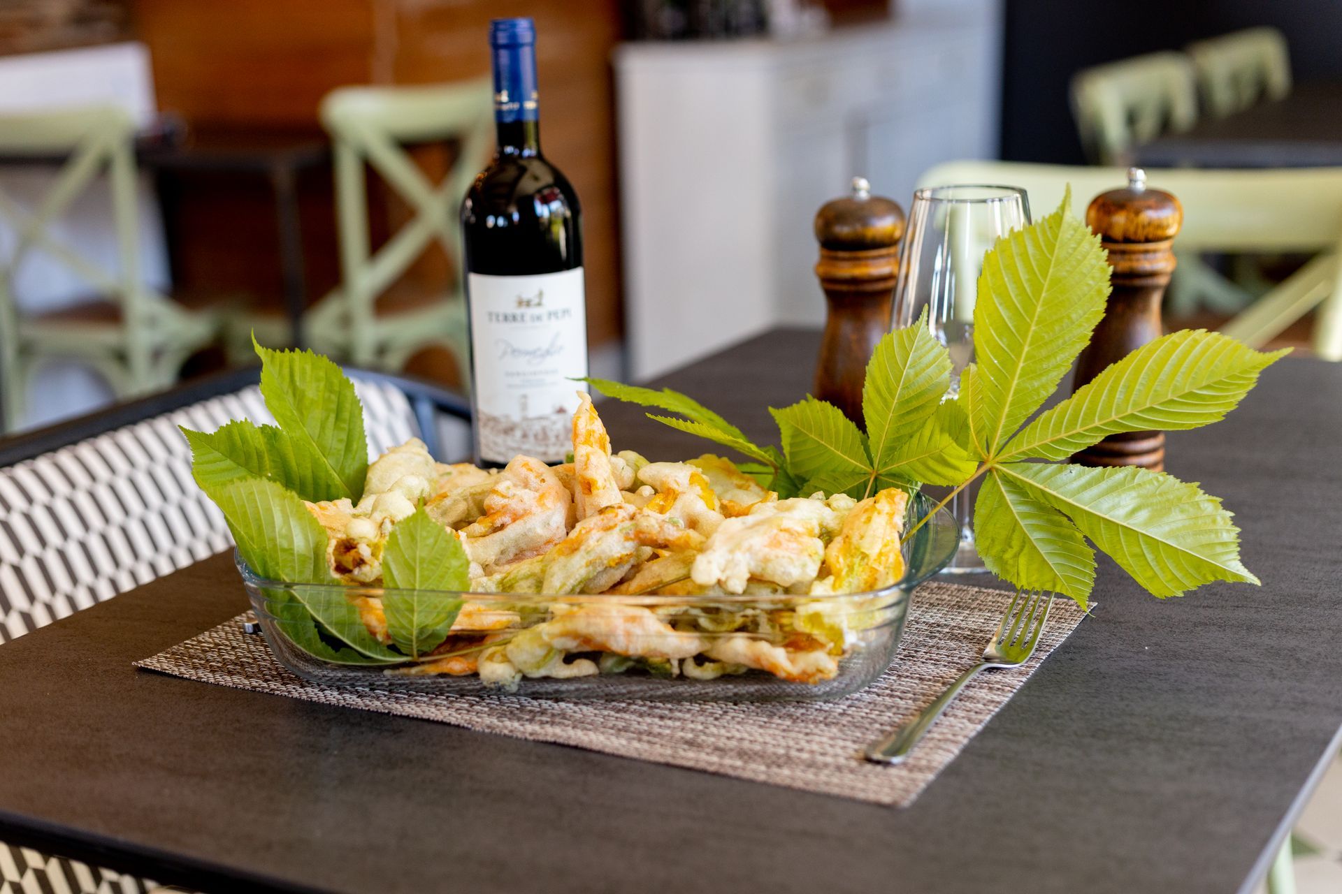 Piatto di frutti di mare con limone su un tavolo, accanto a una bottiglia di vino e un bicchiere, in un ambiente da ristorante.