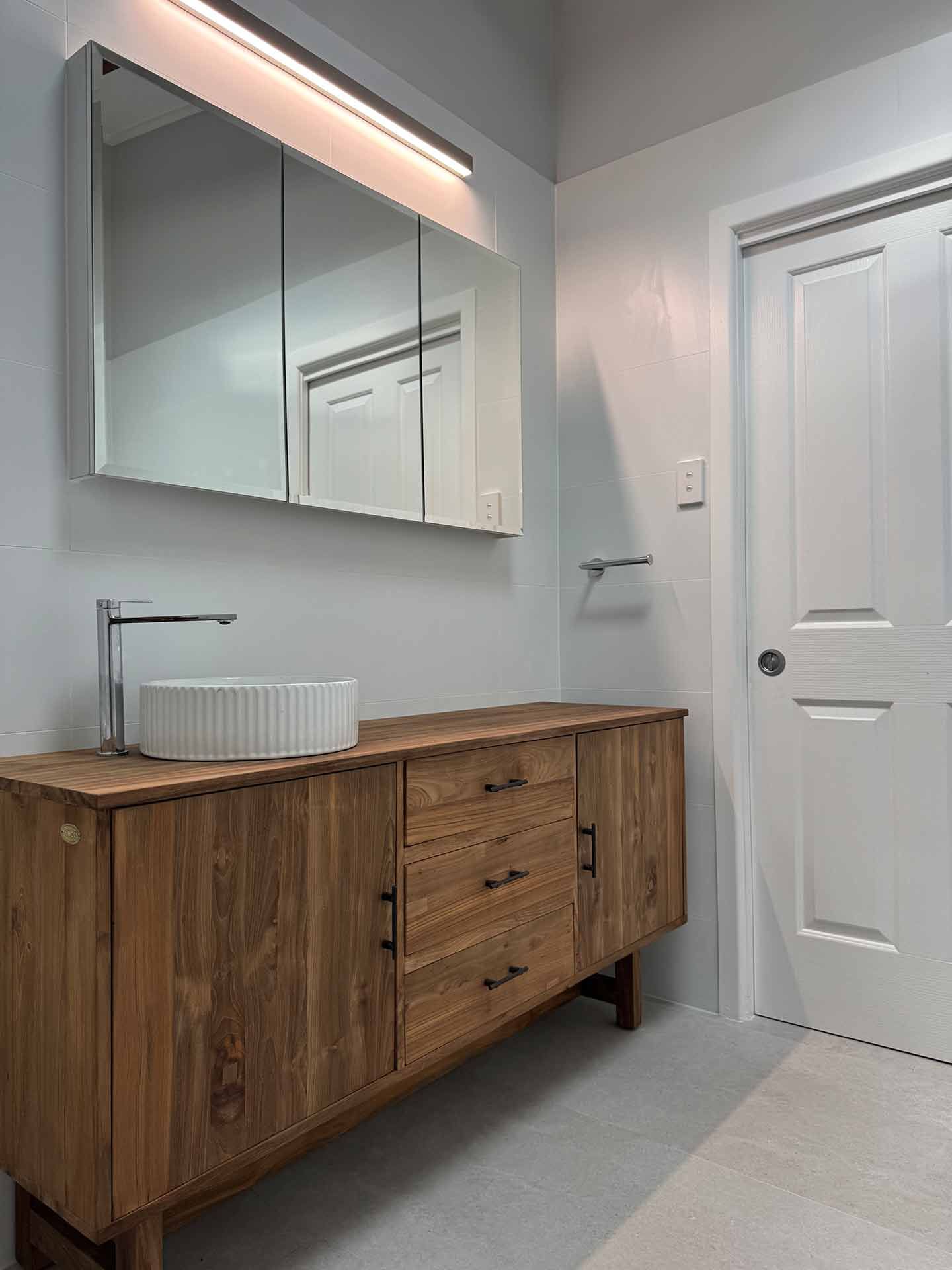 A Bathroom With a Wooden Vanity, Sink and Mirror — Hart Projects Wollongong In Dapto, NSW