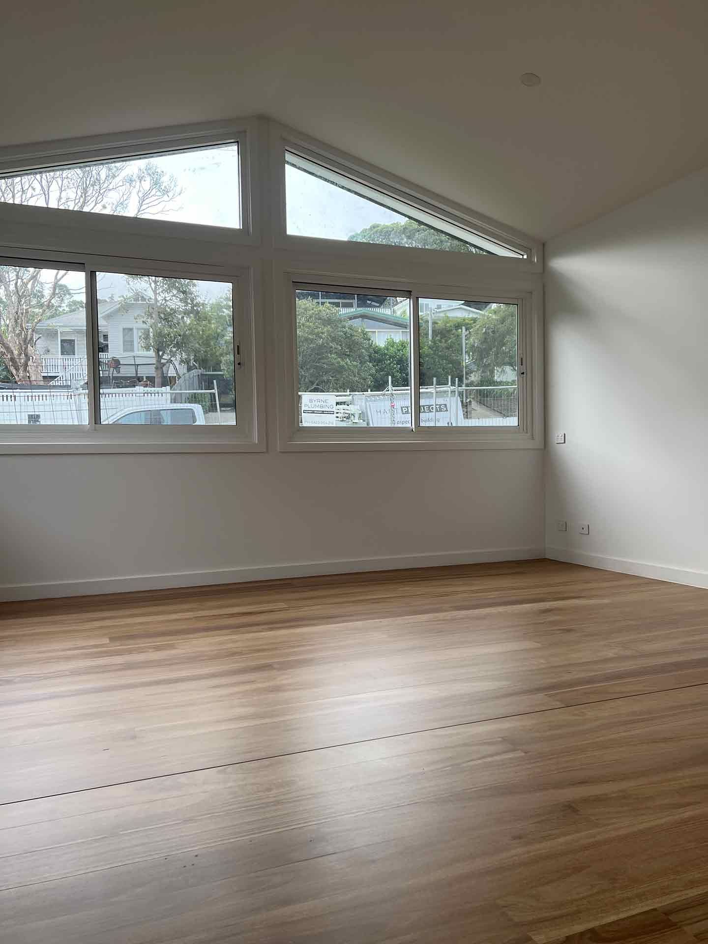 An Empty Living Room With Hardwood Floors — Hart Projects Wollongong In Dapto, NSW