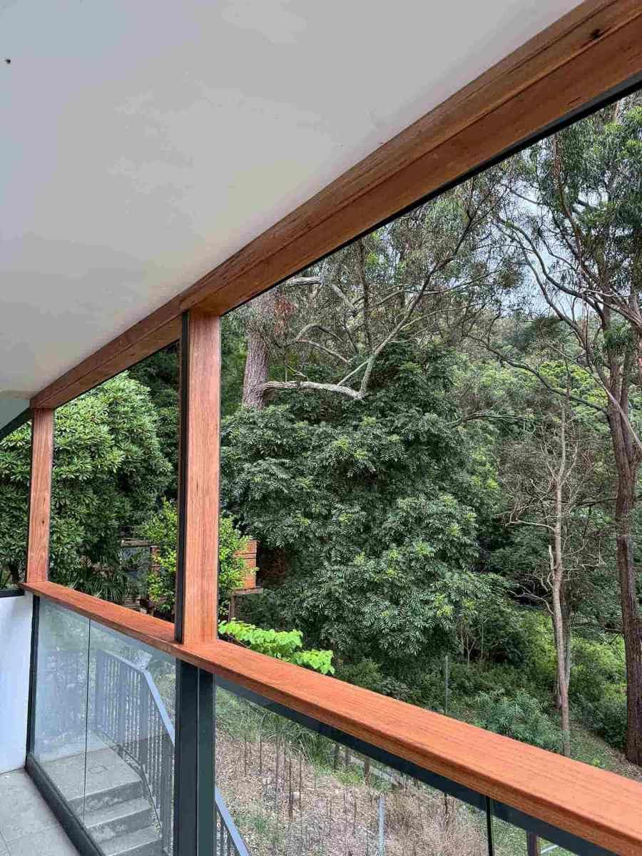 A Balcony With a Wooden Railing and a View of Trees — Hart Projects Wollongong In Dapto, NSW