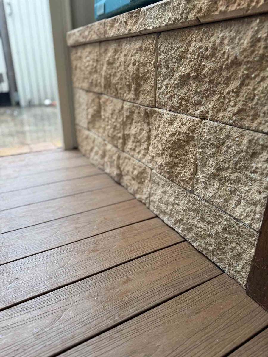 A Wooden Deck With a Brick Wall in the Background — Hart Projects Wollongong In Kiama, NSW