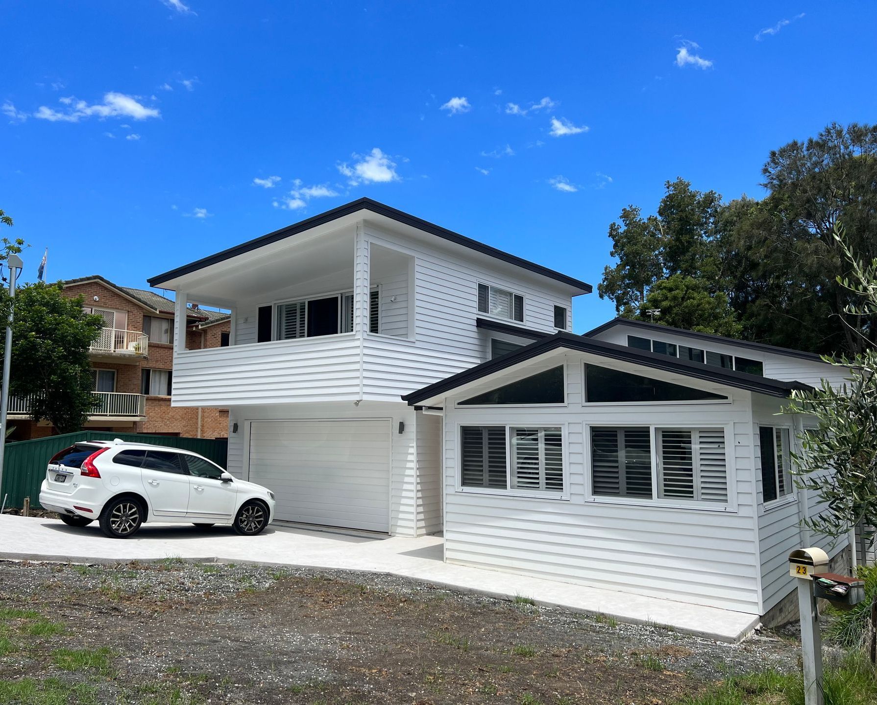 A white car is parked in front of a large white house — Hart Projects Wollongong In Dapto, NSW