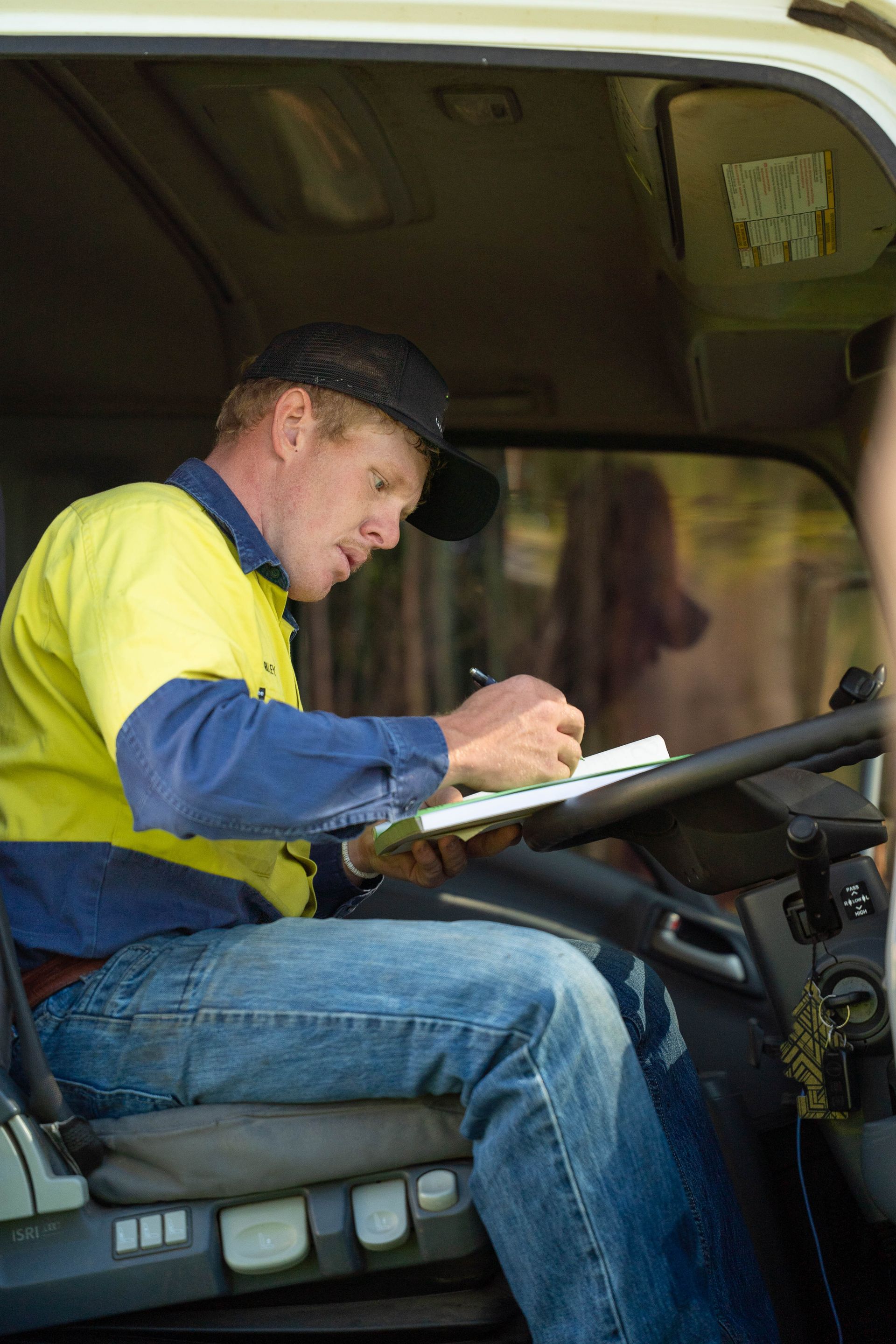 Man Writing on a Clipboard Inside a Truck Cab — Shreks Septic Services in Gowrie Junction, QLD