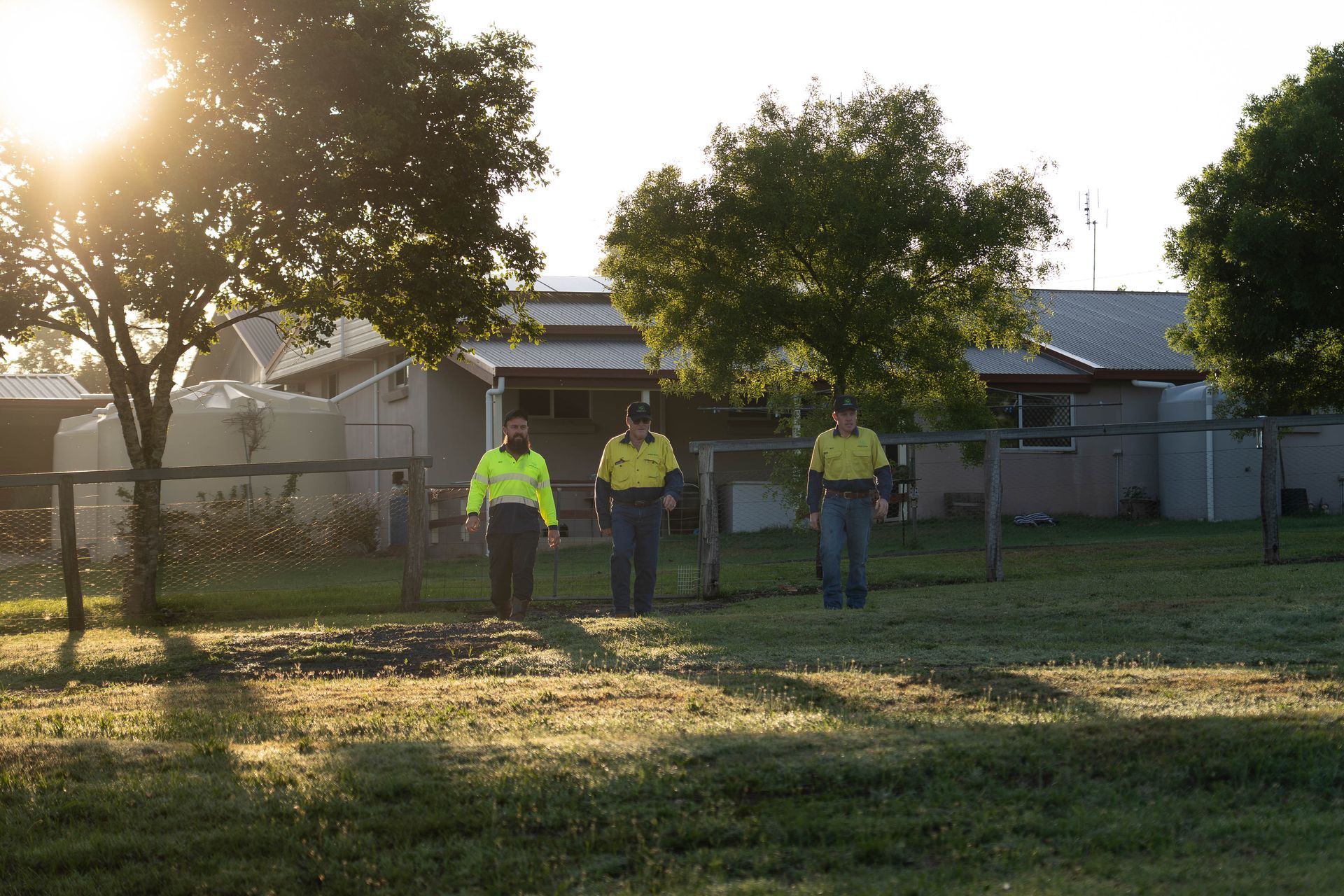 Three People in Bright Shirts Stand in a Grassy Yard — Shreks Septic Services in Gowrie Junction, QLD