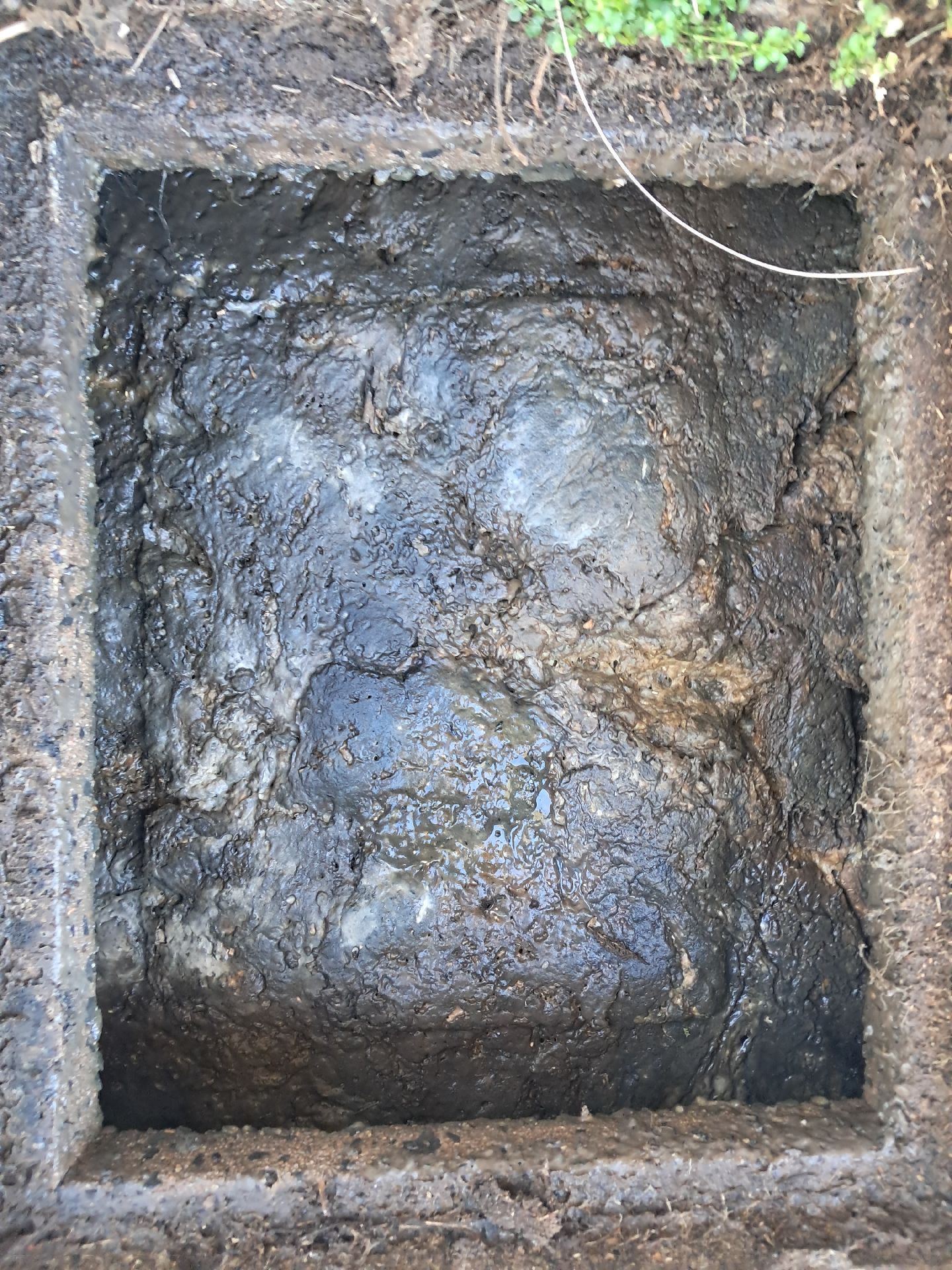 Close-up of a Muddy Square Hole — Shreks Septic Services in Helidon, QLD