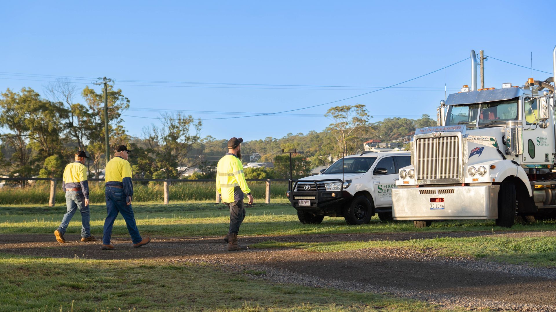 Workers in Yellow Vests Stand Near a White Utility Truck — Shreks Septic Services in Toowoomba, QLD