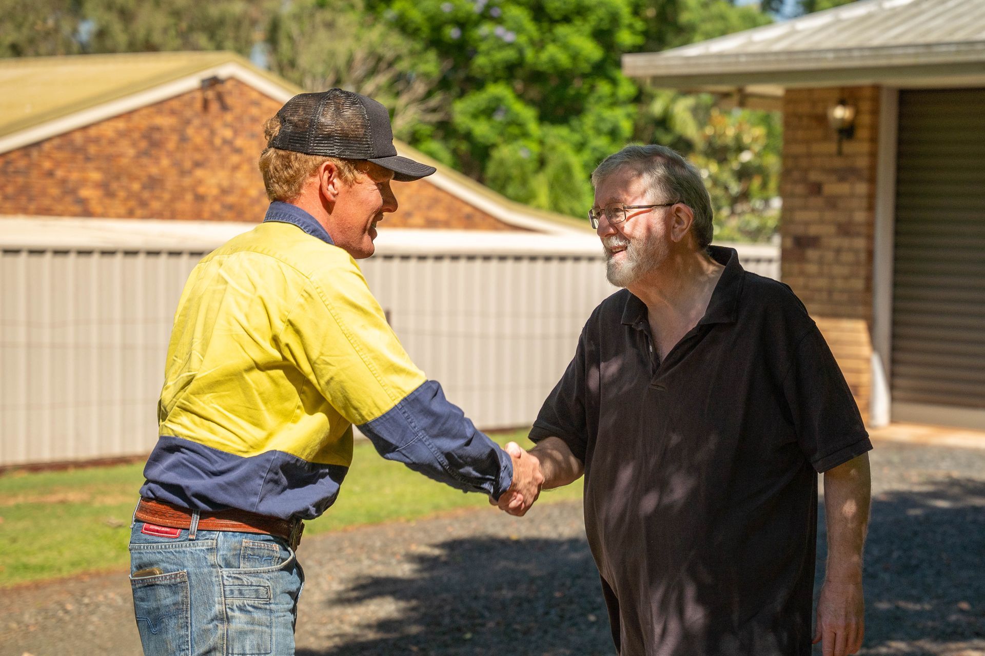 Two Men Shaking Hands Outside a House — Shreks Septic Services in Southbrook, QLD